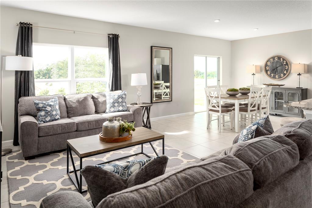 A living room and dining area feature gray sofas, a coffee table, and tile flooring — 1113 LEXINGTON LANE, HAINES CITY, FL