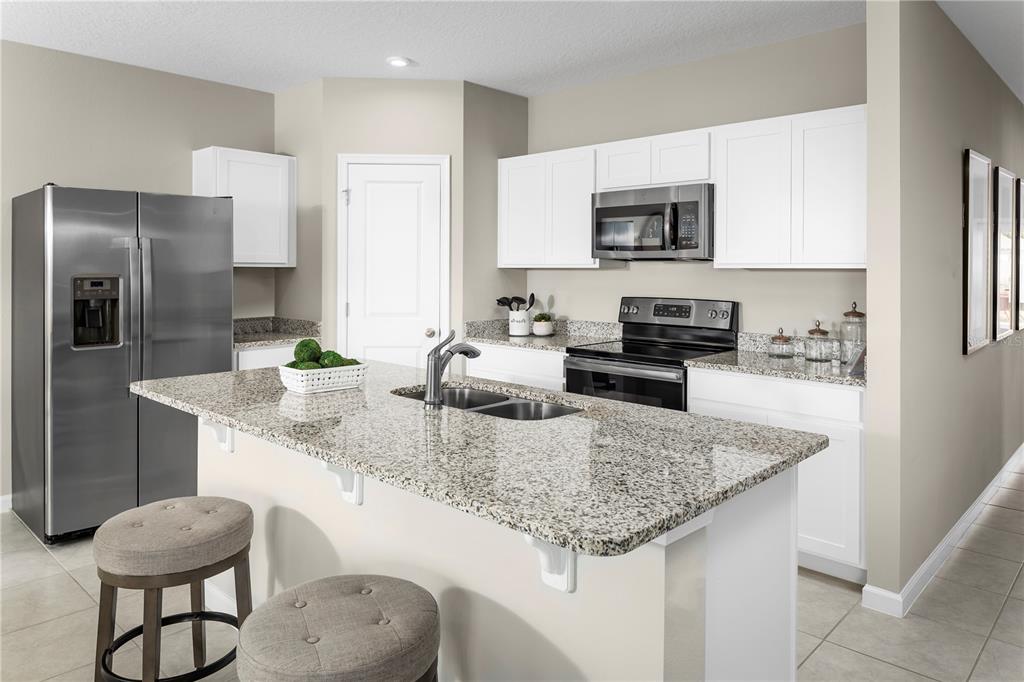 A kitchen features white cabinets, granite countertops, stainless steel appliances, and a central island — 1113 LEXINGTON LANE, HAINES CITY, FL