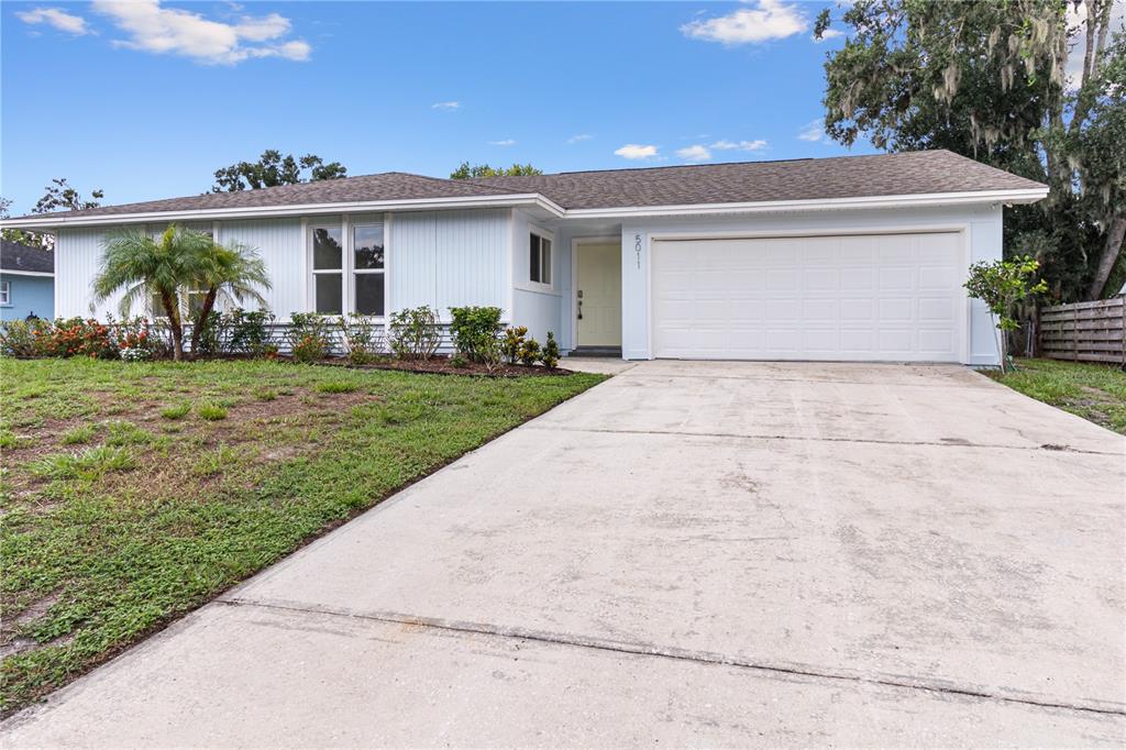 A single-story house with light blue siding, a two-car garage, and a front lawn — 5011 LEON DRIVE, PALMETTO, FL