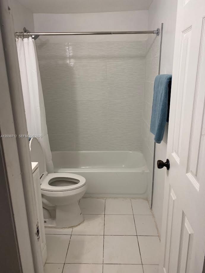 A small bathroom features a white toilet, a bathtub with a shower curtain, and tile flooring — 4717 SW 33rd Ave # 102, Dania Beach FL 33312, DANIA BEACH, FL