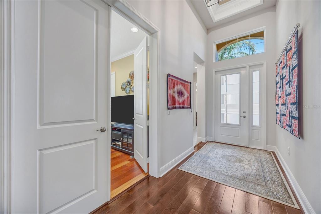 A bright entryway features hardwood floors, a patterned rug, white doors, and wall-mounted textiles — 2415 OAKWOOD PRESERVE DRIVE, WESLEY CHAPEL, FL