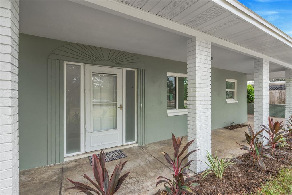 A covered front porch with white brick columns and a sage green exterior wall — 19 VENTURA DRIVE, DUNEDIN, FL