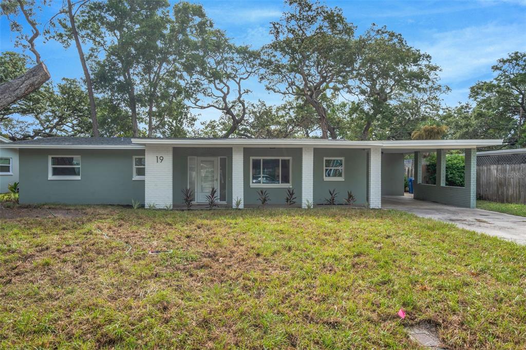 A single-story house with a green exterior, white brick columns, and an attached carport — 19 VENTURA DRIVE, DUNEDIN, FL