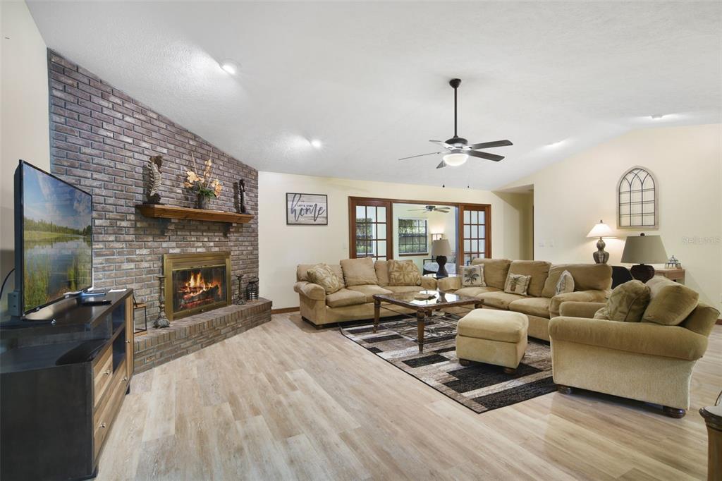 A living room features a brick fireplace, light wood flooring, and a large sectional sofa — 1410 SE 44TH AVENUE, OCALA, FL