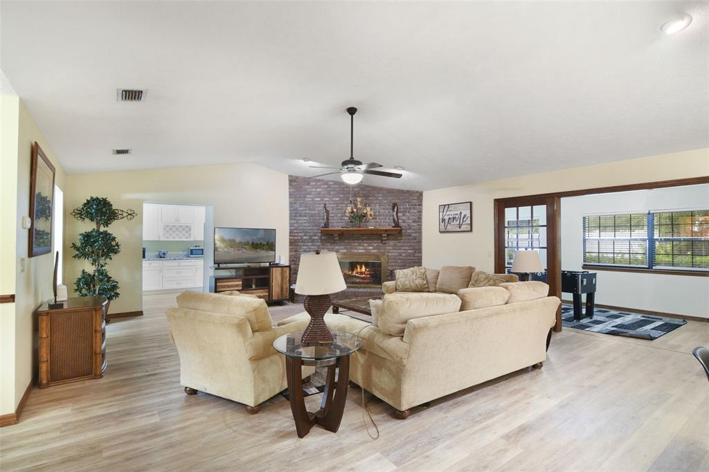 A living room features a brick fireplace, beige sectional sofa, and light wood-look flooring — 1410 SE 44TH AVENUE, OCALA, FL