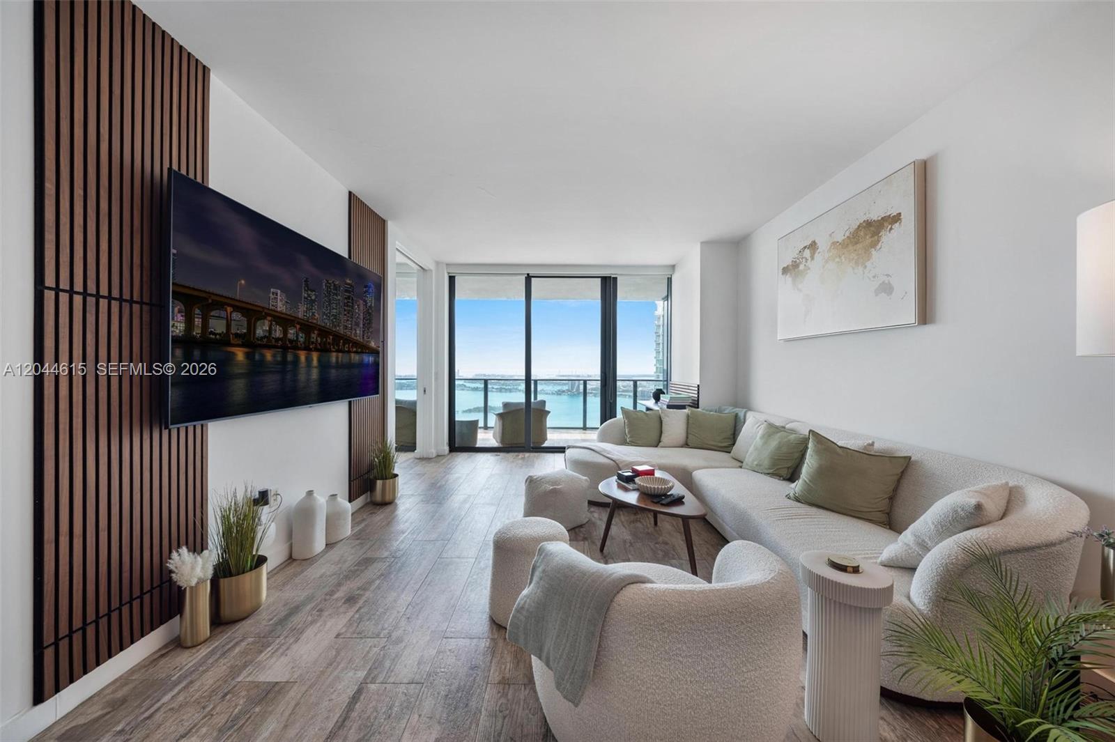 A living room features wood-slat wall paneling, a large television, and a balcony with water views — 650 NE 32nd St # 4805, Miami FL 33137, MIAMI, FL
