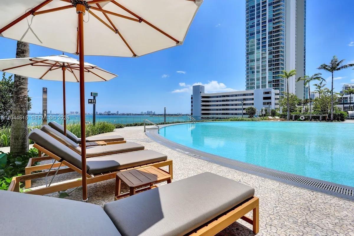 A swimming pool with lounge chairs and umbrellas overlooks the ocean and city skyline — 650 NE 32nd St # 4805, Miami FL 33137, MIAMI, FL