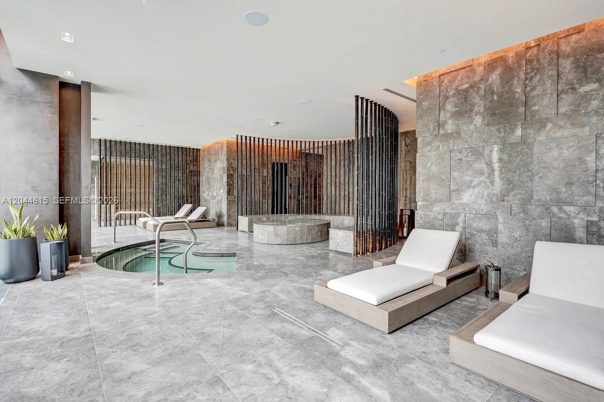 This spa room features a circular hot tub, lounge chairs, and grey stone tile walls — 650 NE 32nd St # 4805, Miami FL 33137, MIAMI, FL