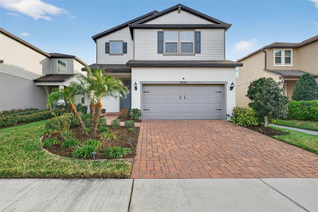A two-story house with a brick paver driveway, a two-car garage, and a palm tree — 18056 AERO AVENUE, LAND O LAKES, FL