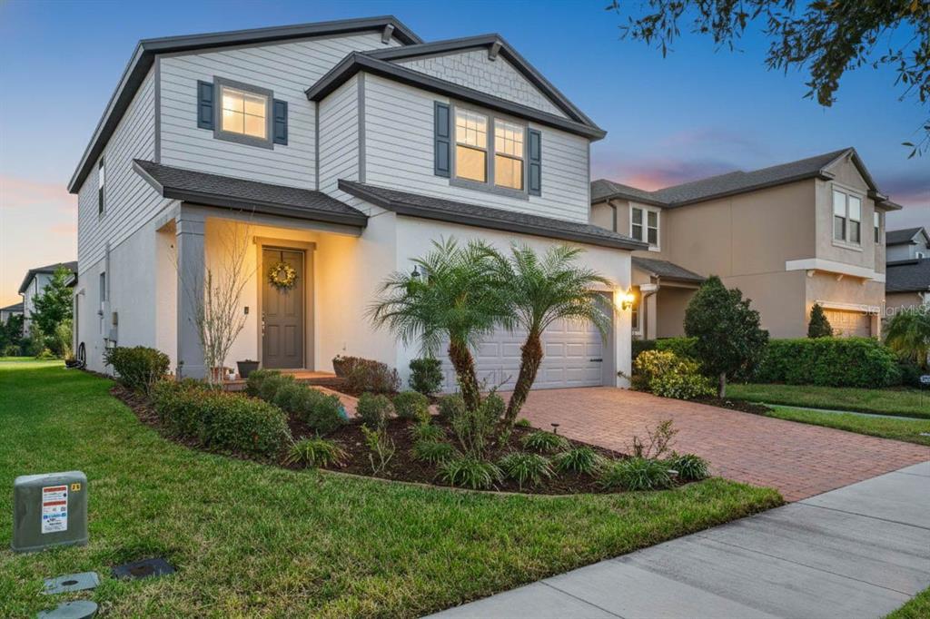 A two-story house with white siding, a brick driveway, and palm trees in the front yard — 18056 AERO AVENUE, LAND O LAKES, FL