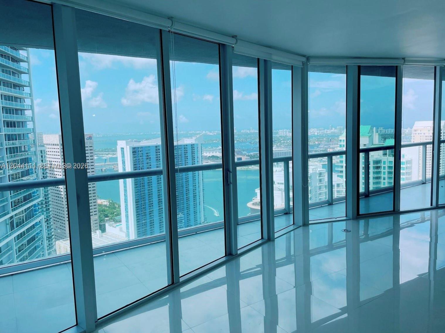 An empty room with floor-to-ceiling windows overlooking a city skyline and the ocean — 495 Brickell Ave # 4804, Miami FL 33131, MIAMI, FL