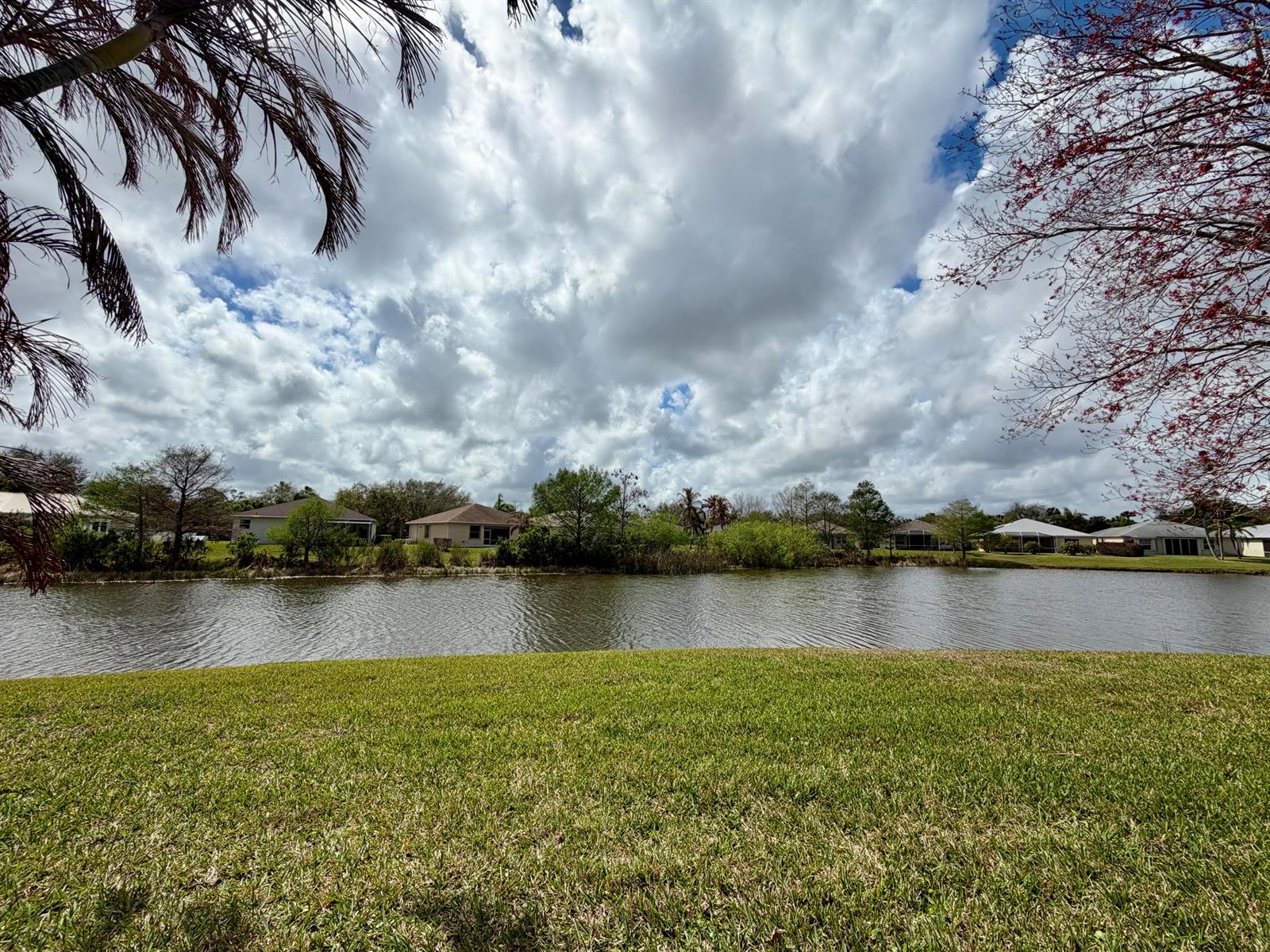 A view of a lake with houses in the background under a cloudy sky — 6295 33rd Manor, Vero Beach FL 32966, VERO BEACH, FL