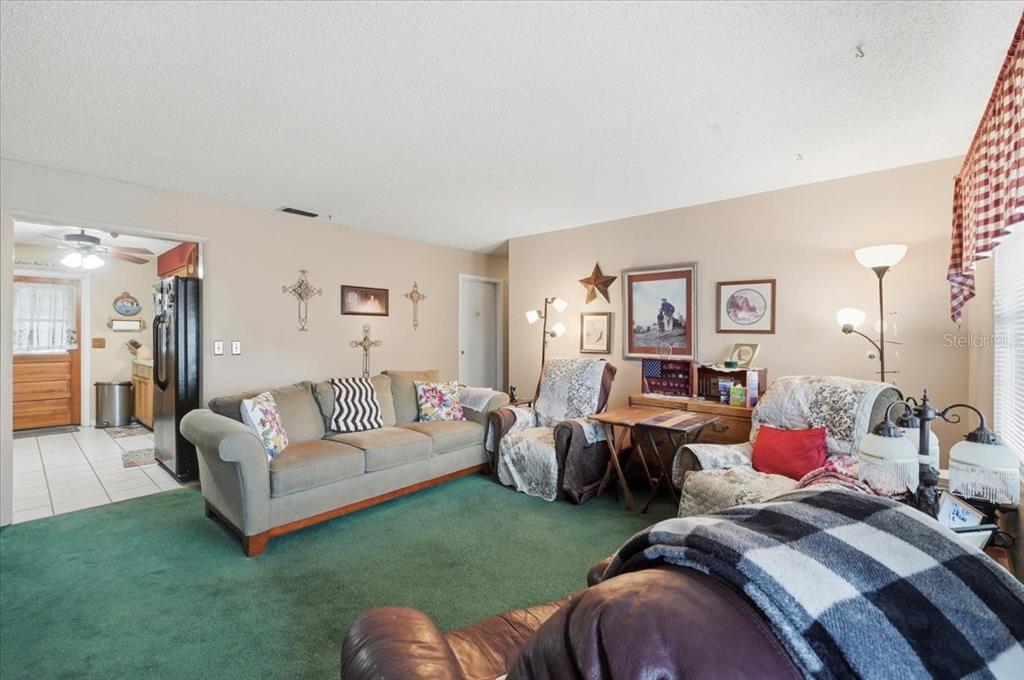 A living room features green carpeting, a beige sofa, two armchairs, and wall-mounted crosses — 626 CORTEZ STREET, LAKELAND, FL