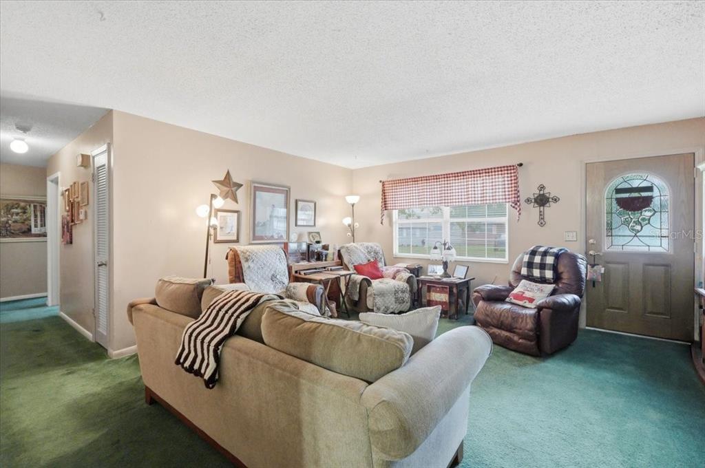 A living room features green carpeting, a beige sofa, two armchairs, and a front door — 626 CORTEZ STREET, LAKELAND, FL