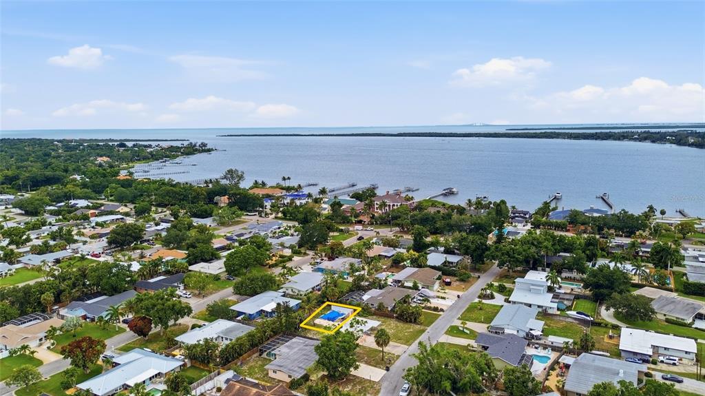 An aerial view shows a residential neighborhood near a bay with a highlighted swimming pool — 1308 62ND STREET NW, BRADENTON, FL