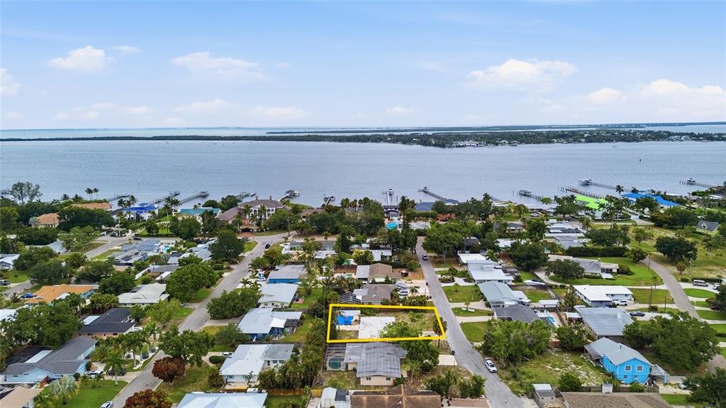 An aerial view shows a vacant residential lot outlined in yellow near a waterfront neighborhood — 1308 62ND STREET NW, BRADENTON, FL