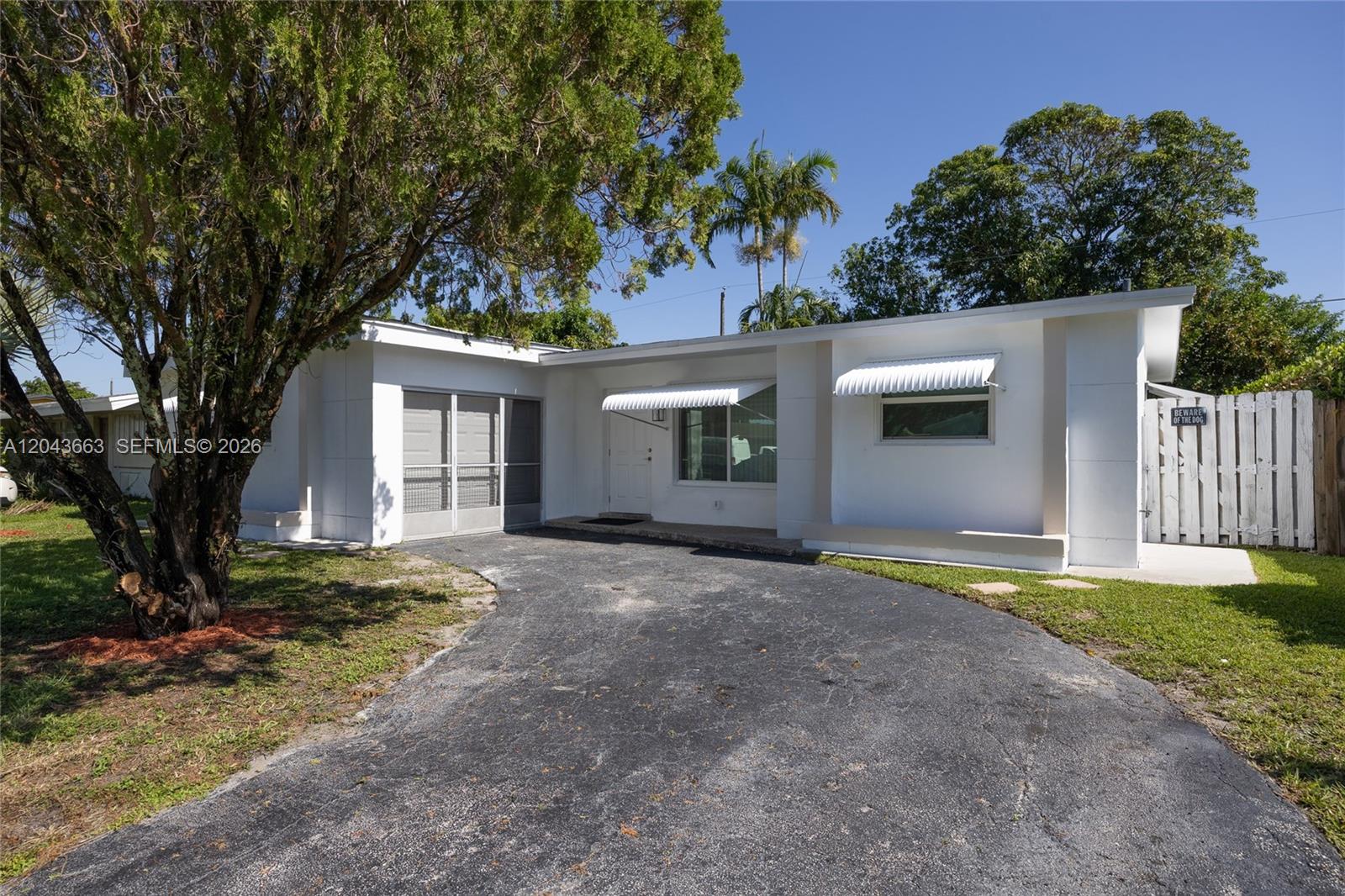 A white single-story house features a curved asphalt driveway and two metal window awnings — 8571 NW 27th Pl, Sunrise FL 33322, SUNRISE, FL