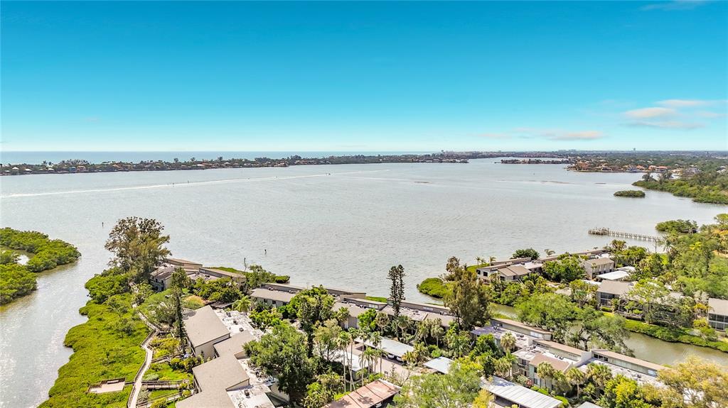 An aerial view shows a waterfront residential complex surrounded by mangroves and a large bay — 1515 PELICAN POINT DRIVE UNIT BA185, SARASOTA, FL