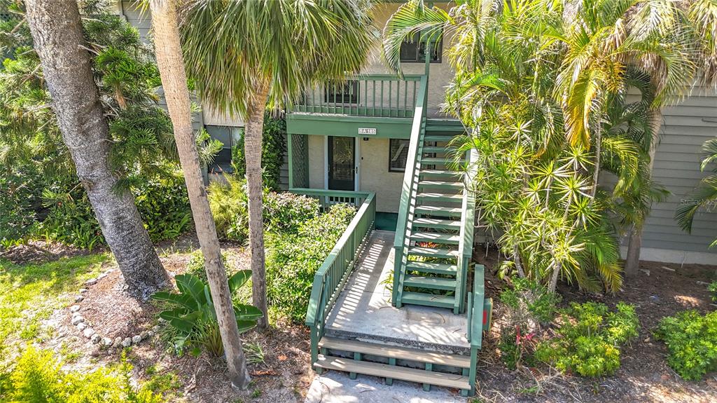 An exterior view of a multi-story building with a wooden staircase leading to a balcony — 1515 PELICAN POINT DRIVE UNIT BA185, SARASOTA, FL