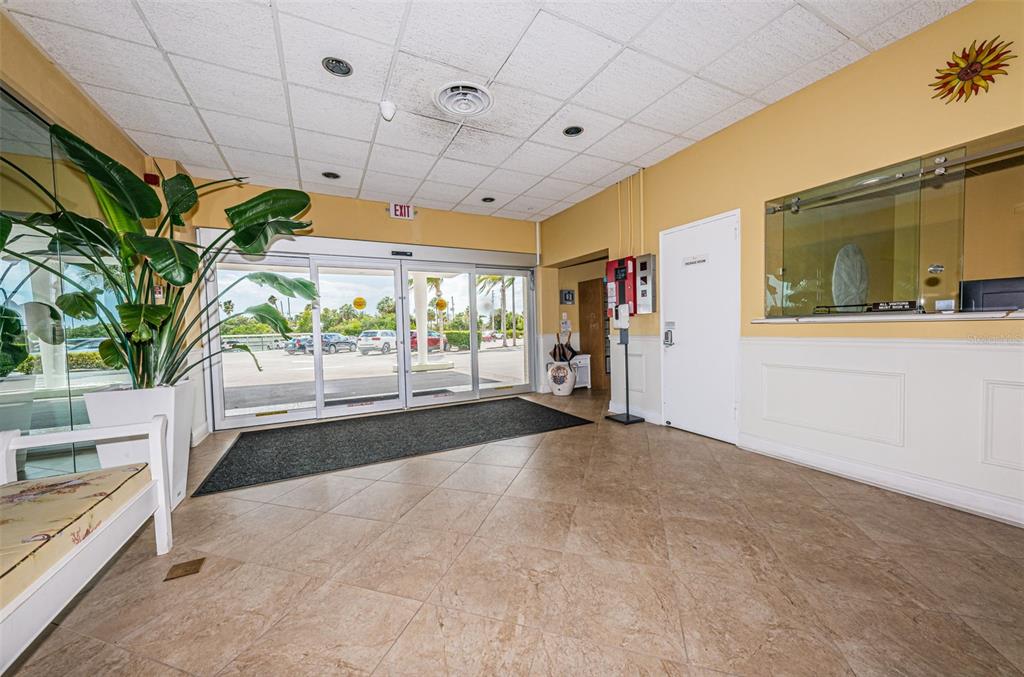 A lobby features tiled floors, a reception desk, sliding glass doors, and a large potted plant — 31 ISLAND WAY UNIT 605, CLEARWATER BEACH, FL
