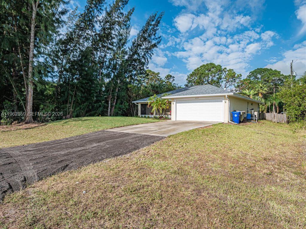 A single-story house features a white garage door, a concrete driveway, and a grassy yard — 8265 97th Ave, Vero Beach FL 32967, VERO BEACH, FL