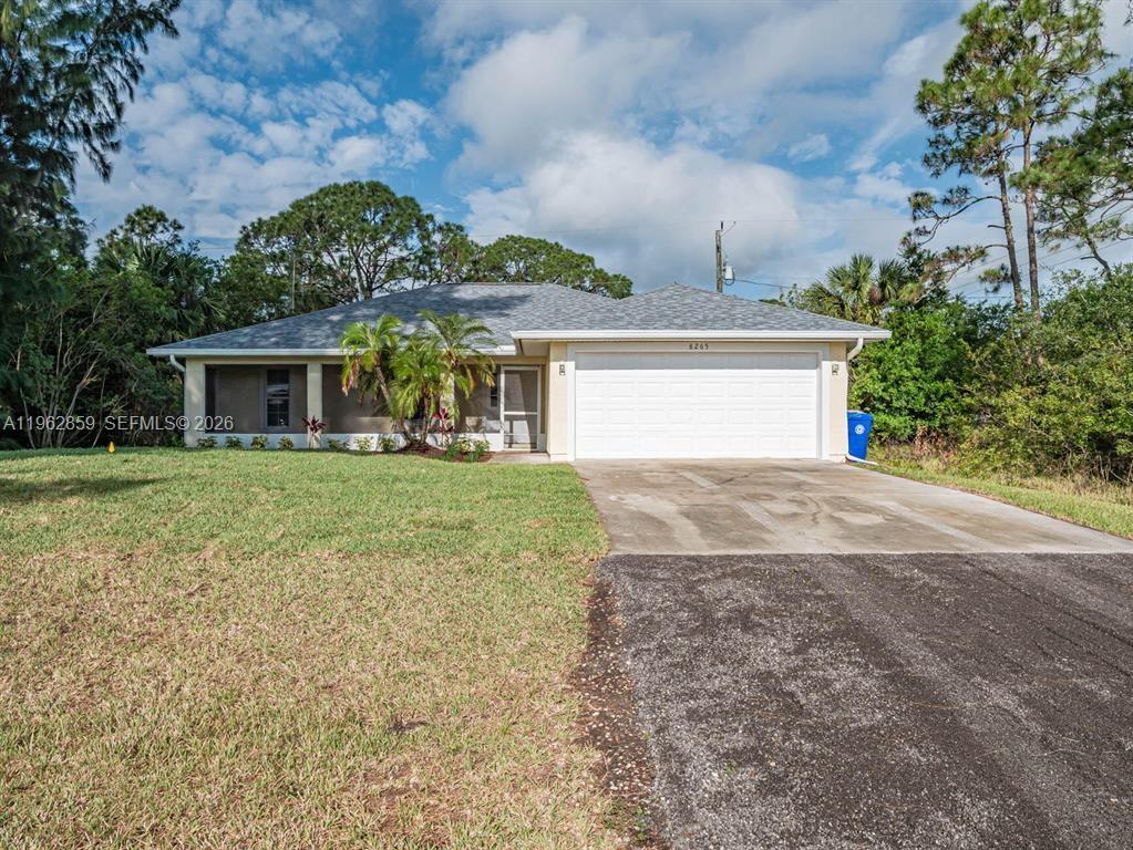 A single-story house with a white garage door and a palm tree in the front yard — 8265 97th Ave, Vero Beach FL 32967, VERO BEACH, FL