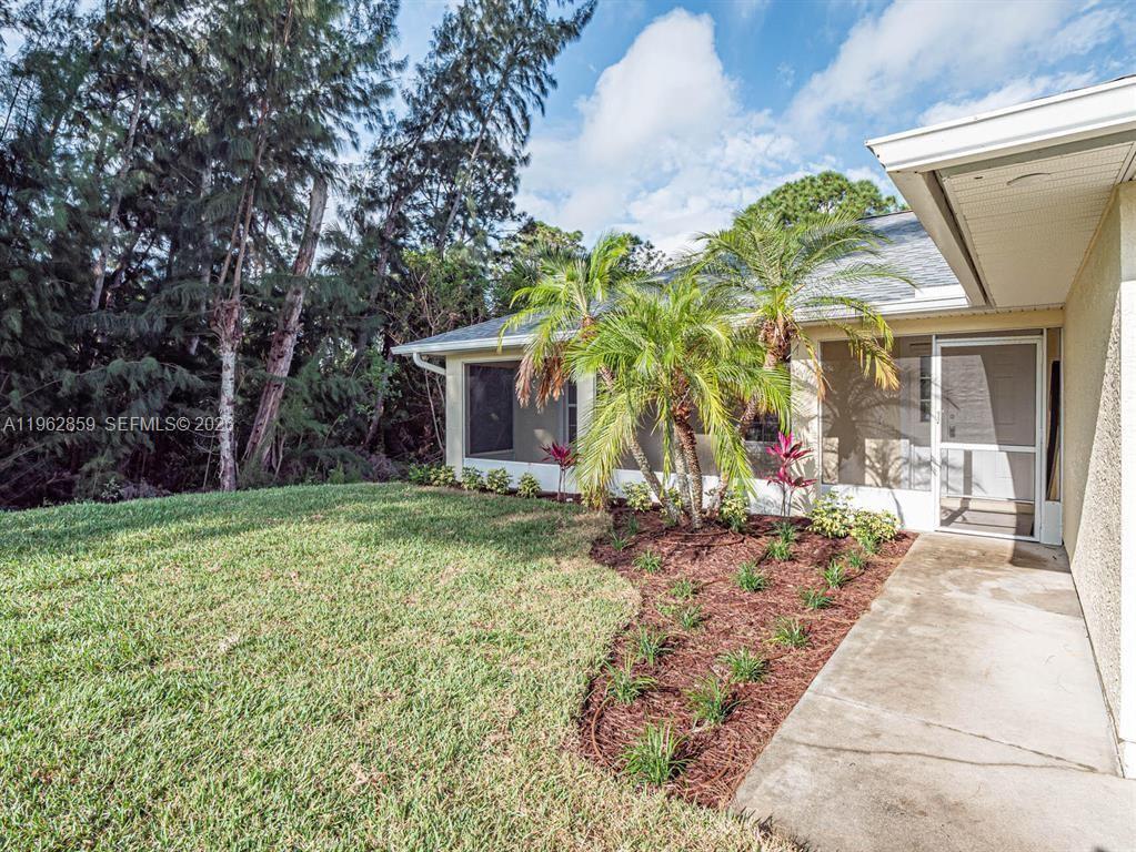 A concrete walkway leads to a screened-in patio area with palm trees and landscaping — 8265 97th Ave, Vero Beach FL 32967, VERO BEACH, FL
