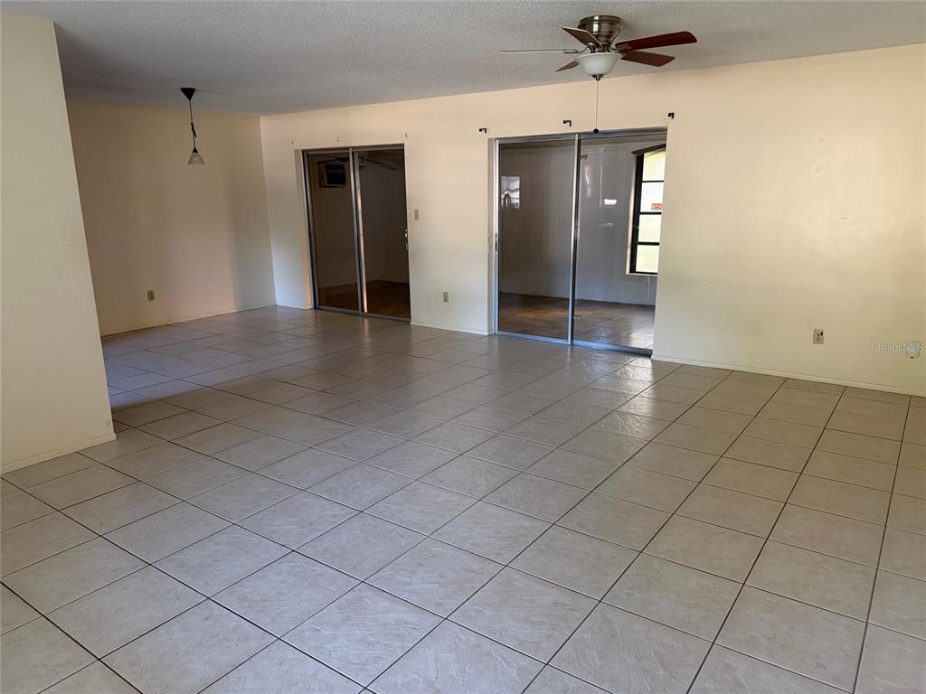 A spacious living area features light-colored floor tiles, a ceiling fan, and two sliding doors — 4805 LANDOVER CIRCLE, ORLANDO, FL