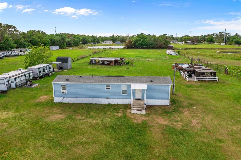 An aerial view shows a blue mobile home on a large, grassy rural lot — 3834 HIXON AVENUE, ST CLOUD, FL