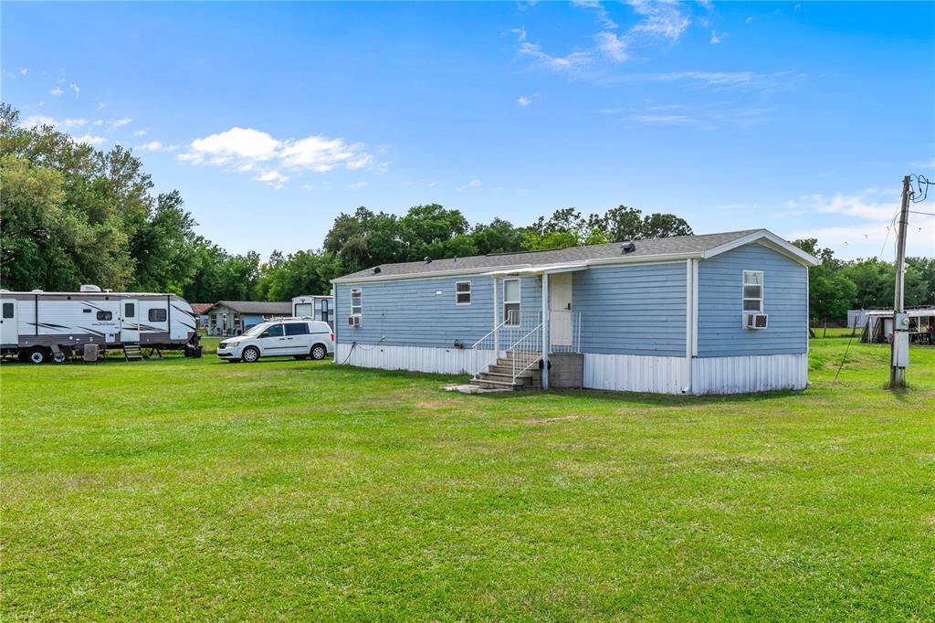 A blue mobile home sits on a large grassy lot with a white van nearby — 3834 HIXON AVENUE, ST CLOUD, FL
