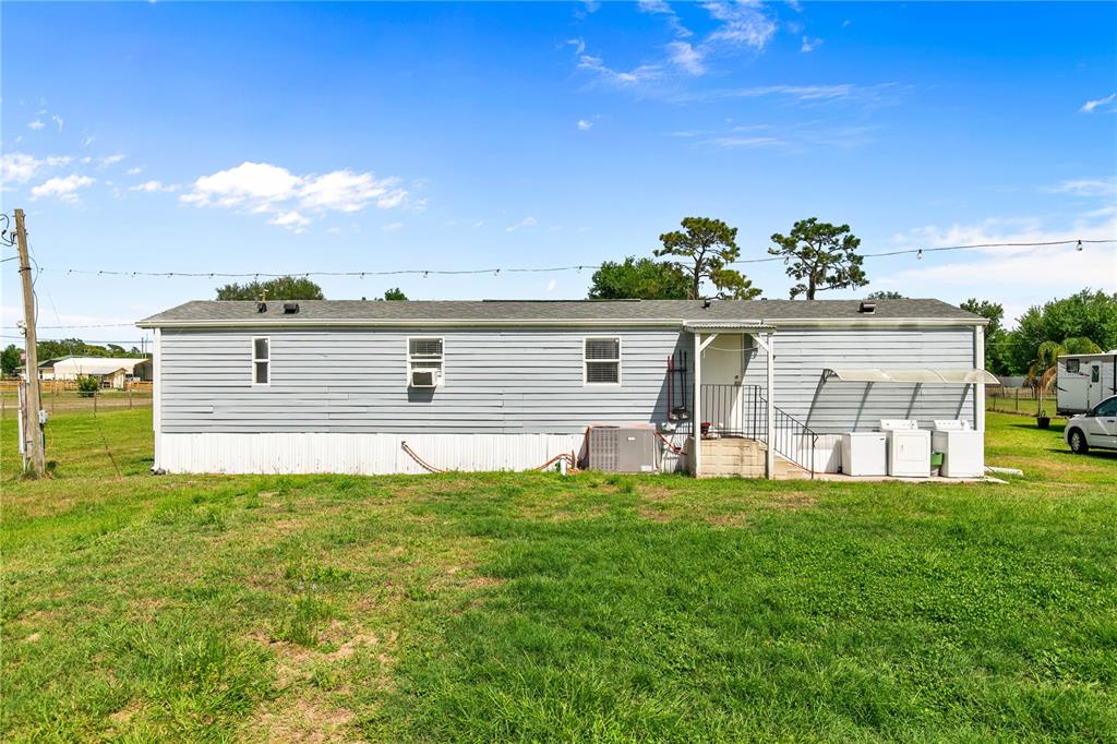 The exterior of a light blue manufactured home features a small porch and laundry appliances — 3834 HIXON AVENUE, ST CLOUD, FL
