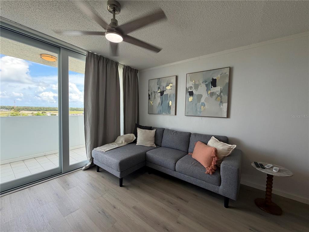 A living room features a gray sectional sofa, abstract wall art, and a sliding glass door — 190 MARGINAL LOS ANGELES UNIT 8, CAROLINA, PR