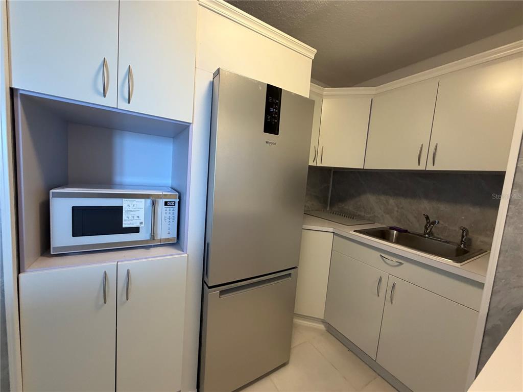 A kitchen features white cabinetry, a stainless steel refrigerator, a microwave, and a sink — 190 MARGINAL LOS ANGELES UNIT 8, CAROLINA, PR