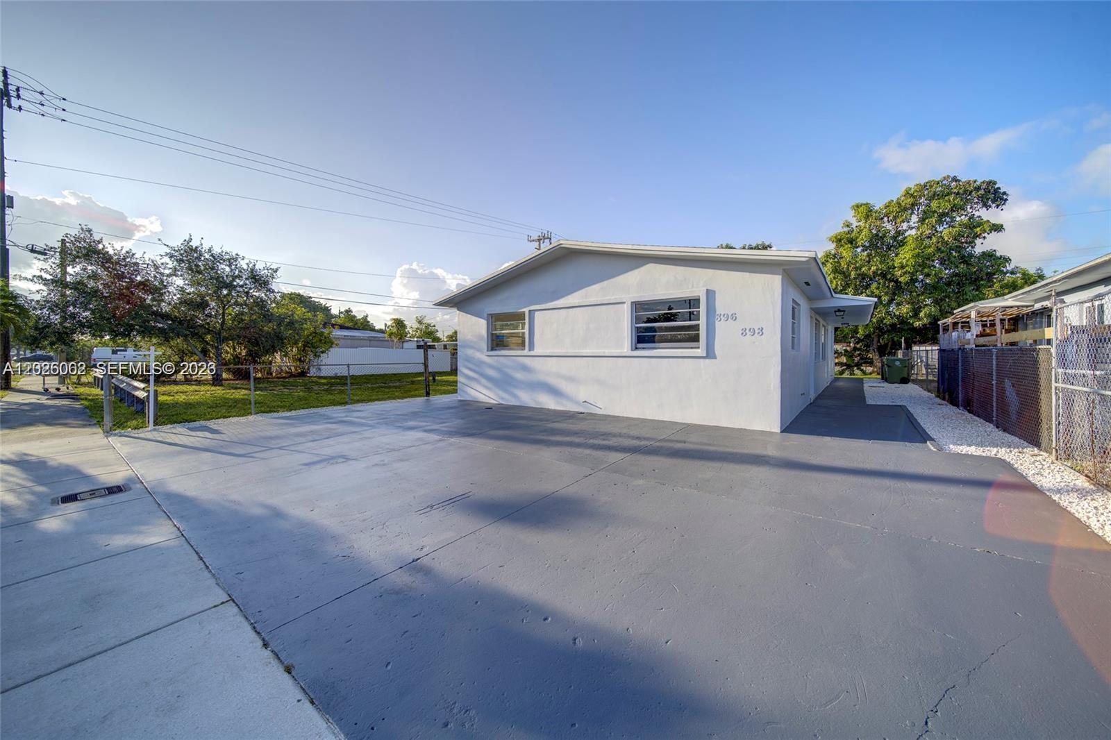 A white single-story house features a large gray concrete driveway and a chain-link fence — 896 E 22nd St # 898, Hialeah FL 33013, HIALEAH, FL