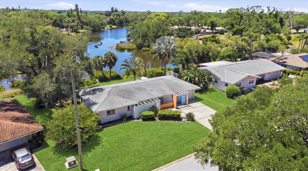 An aerial view shows two single-story houses with gray roofs near a small lake — 2940 BOUGAINVILLEA STREET, SARASOTA, FL