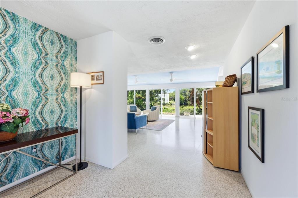 A bright entryway with patterned wallpaper leads into a living room with large glass doors — 2940 BOUGAINVILLEA STREET, SARASOTA, FL