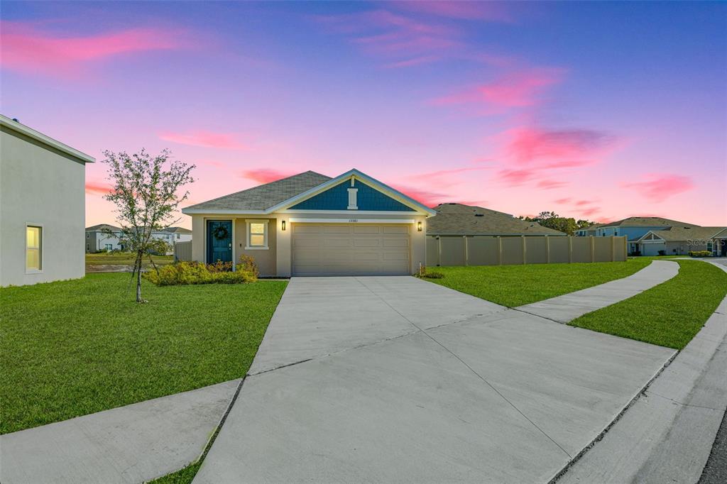 A single-story house with a blue front door, two-car garage, and a concrete driveway — 13581 MOUNT IVY COURT, DADE CITY, FL