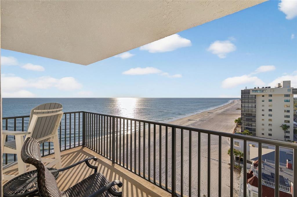 A balcony with outdoor chairs overlooks a sandy beach and the ocean — 15316 GULF BOULEVARD UNIT 903, MADEIRA BEACH, FL