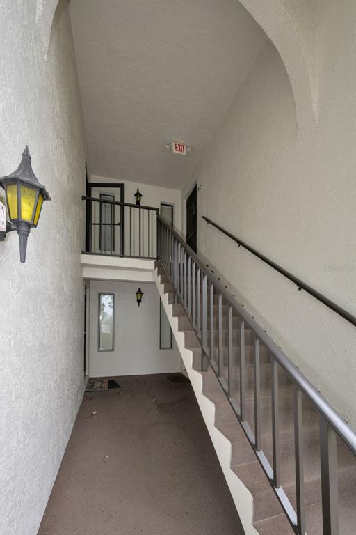 An outdoor staircase with metal railings leads to an upper-level landing with an exit sign — 2687 PINE RIDGE WAY S UNIT B2, PALM HARBOR, FL