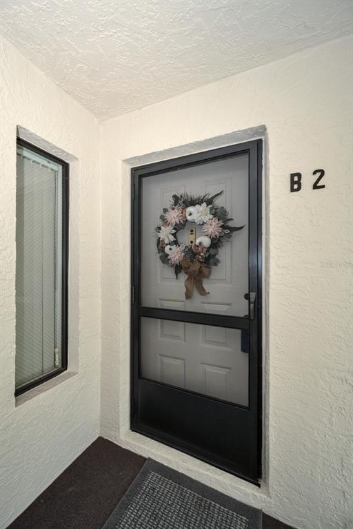 An exterior view of a residential entrance door labeled B2 with a decorative floral wreath — 2687 PINE RIDGE WAY S UNIT B2, PALM HARBOR, FL