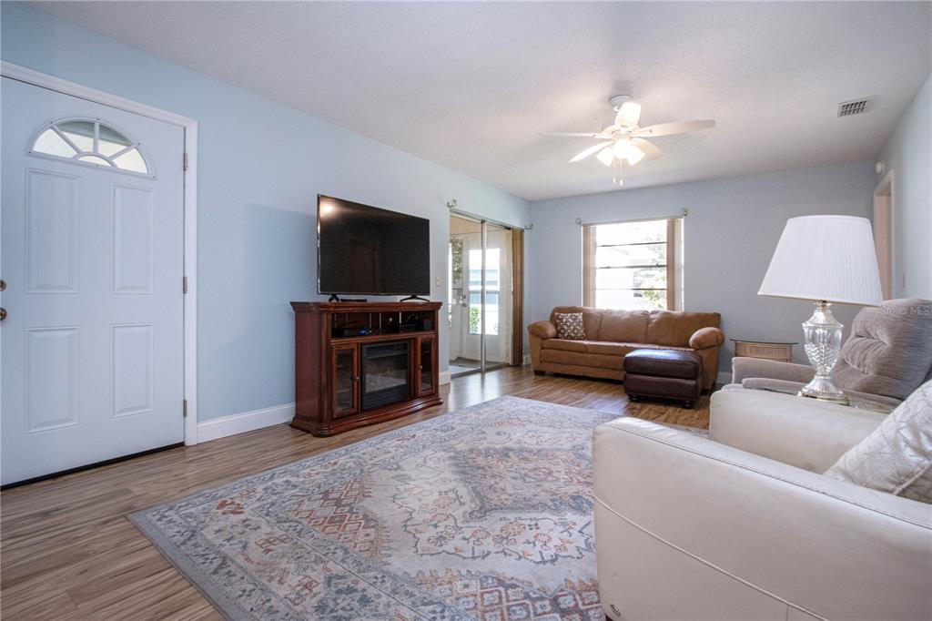 A living room features light blue walls, wood-look flooring, a ceiling fan, and area rug — 2017 HULLHOUSE DRIVE UNIT 351, SUN CITY CENTER, FL