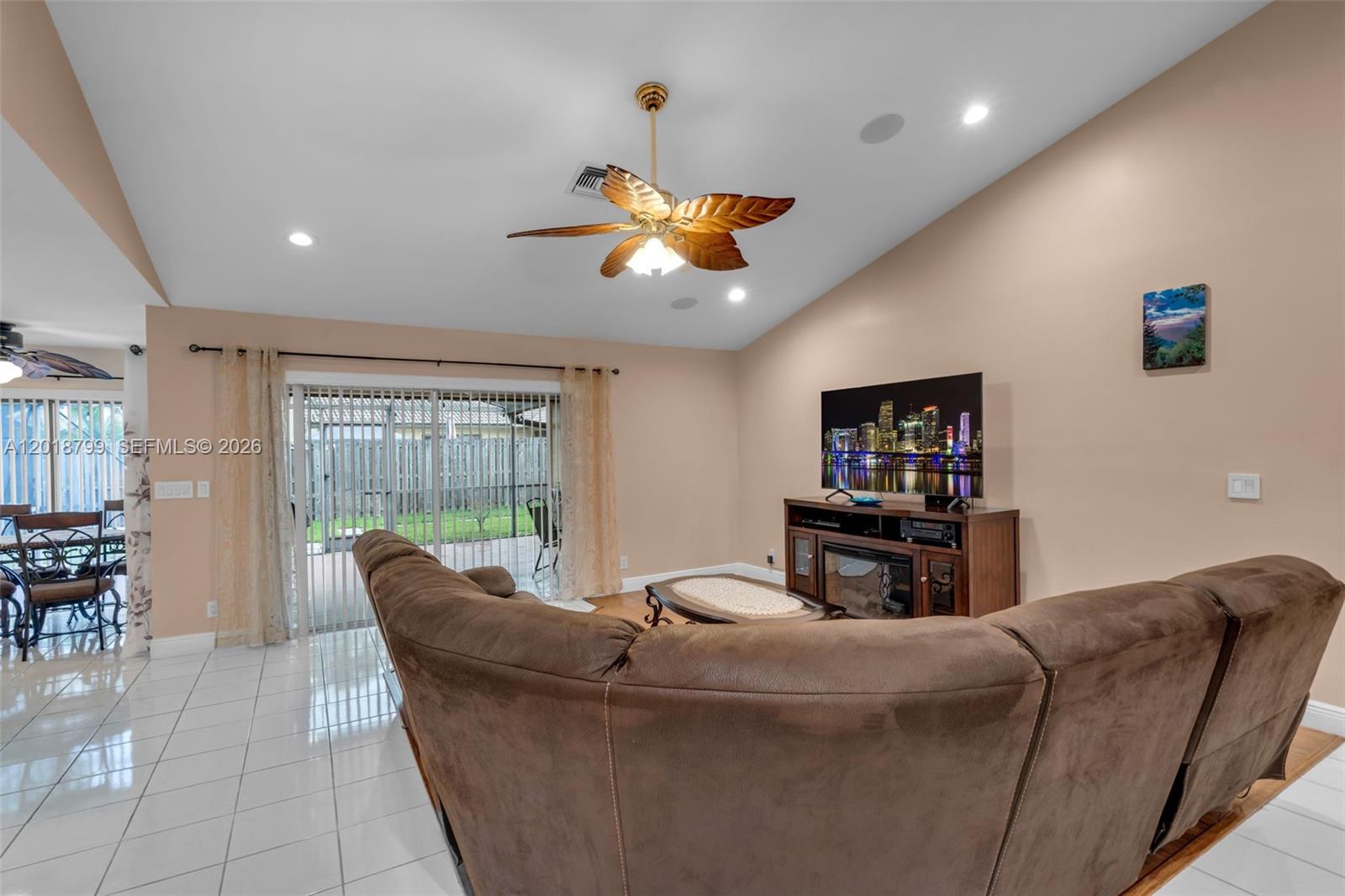 A living room features a brown sectional sofa, a television on a console, and tile flooring — 7817 Sunflower Dr, Margate FL 33063, MARGATE, FL
