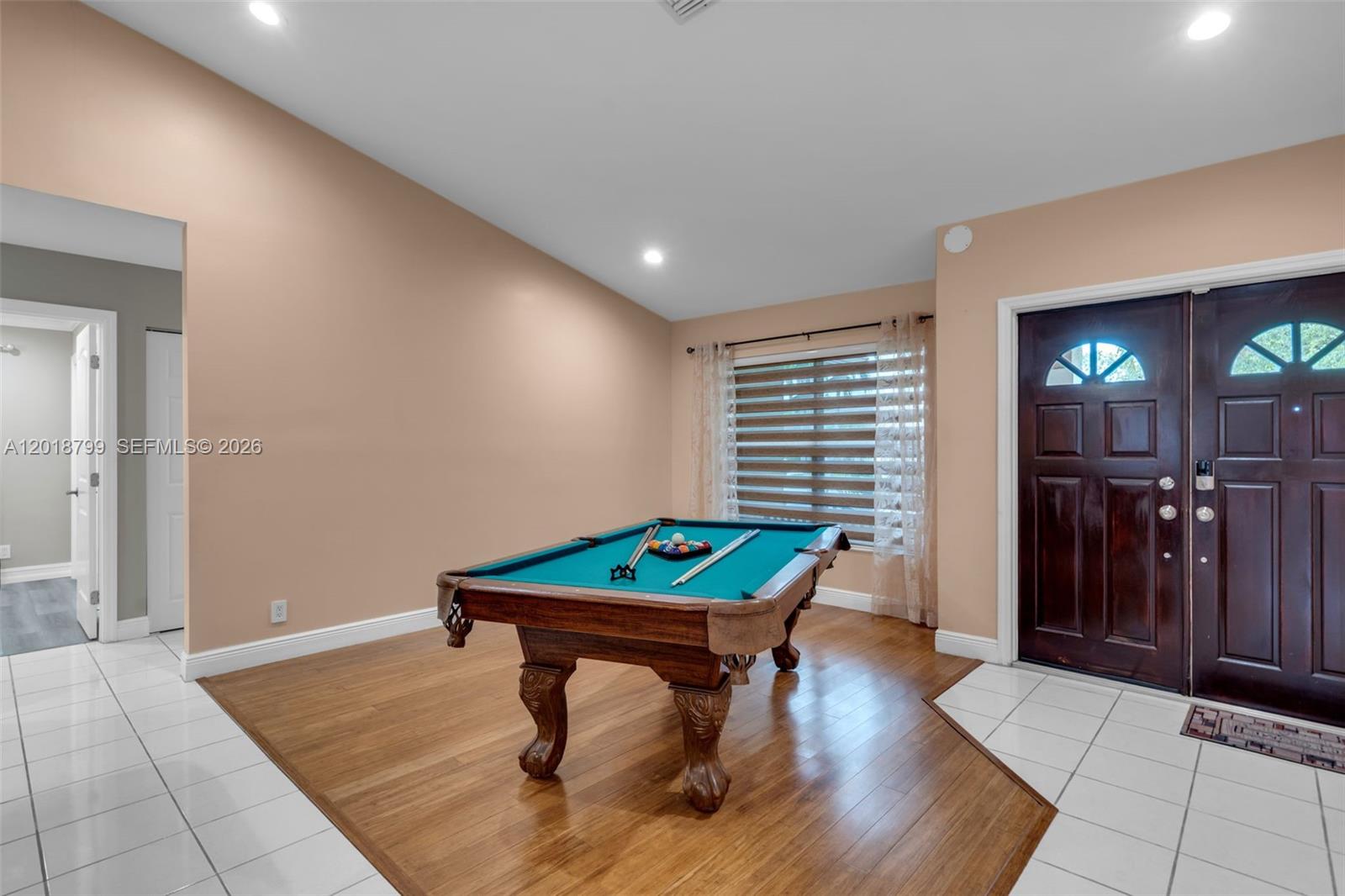 A room with a pool table, wood flooring, and a dark wood front door — 7817 Sunflower Dr, Margate FL 33063, MARGATE, FL