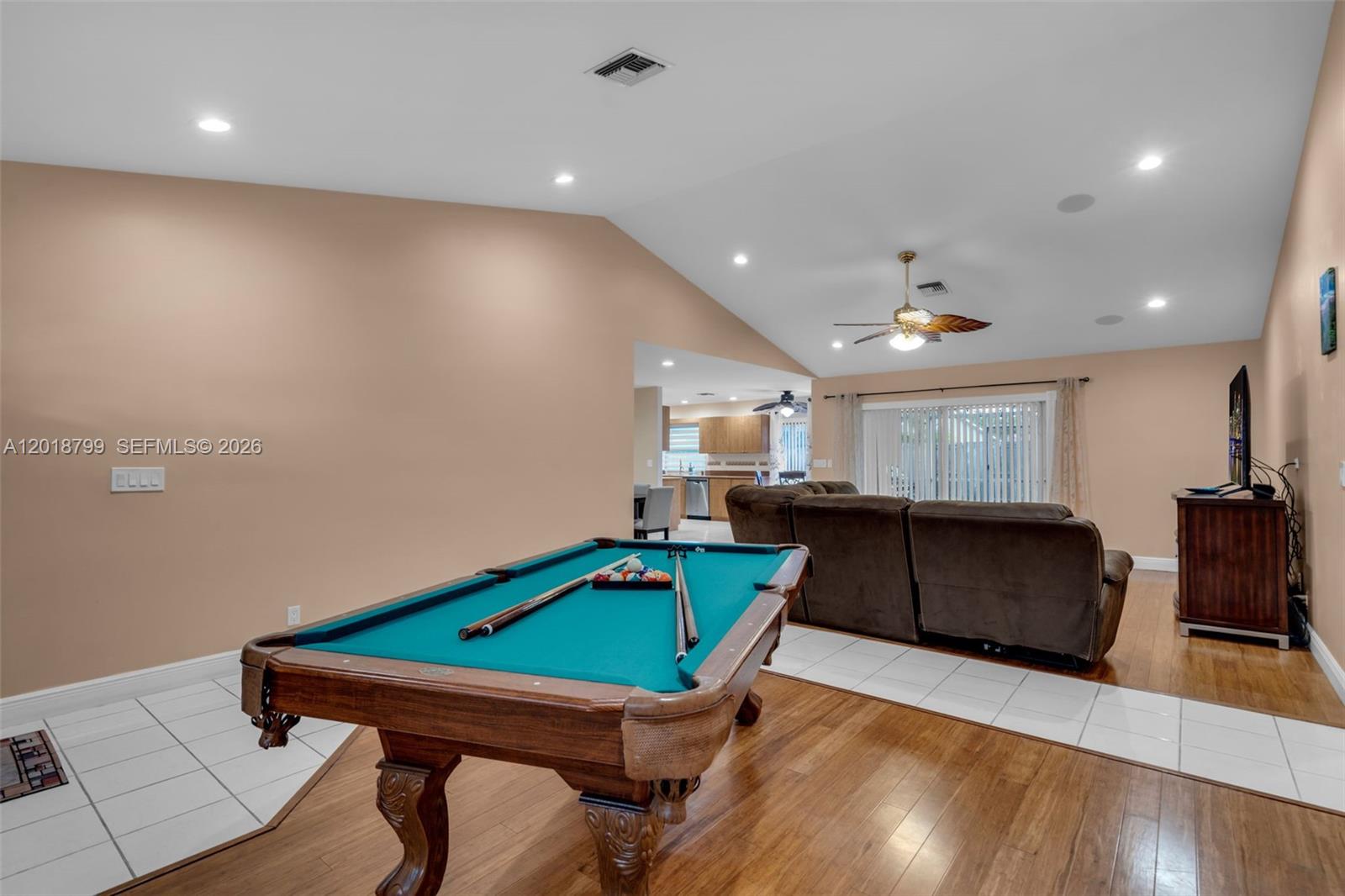 A living room with a pool table, hardwood flooring, and a view into the kitchen — 7817 Sunflower Dr, Margate FL 33063, MARGATE, FL