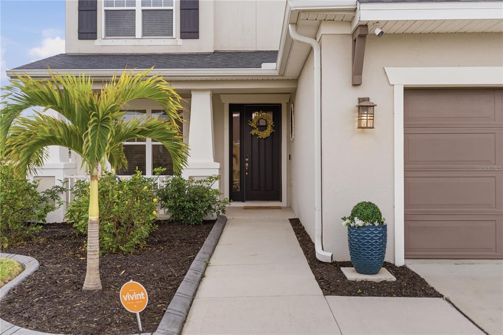The exterior of a house features a front door, a garage, and a palm tree — 4939 LOS ROBLES COURT, PALMETTO, FL