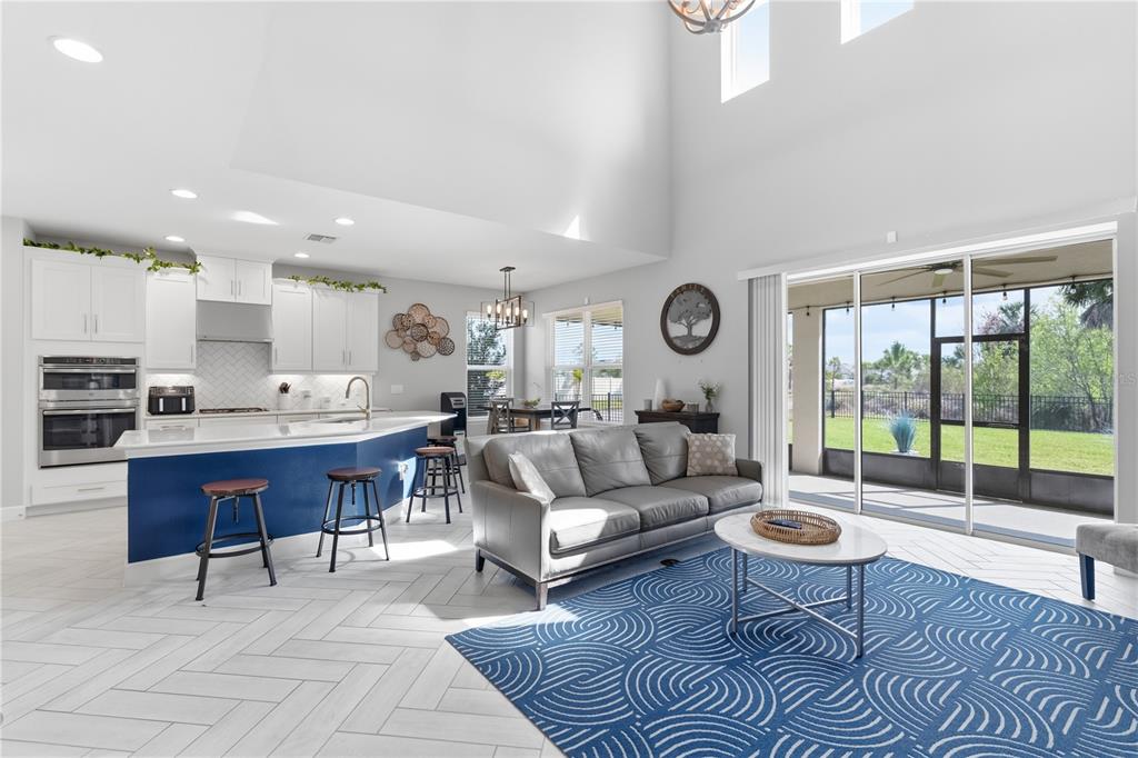 An open-concept living room and kitchen with white cabinetry, a blue island, and sliding doors — 4939 LOS ROBLES COURT, PALMETTO, FL