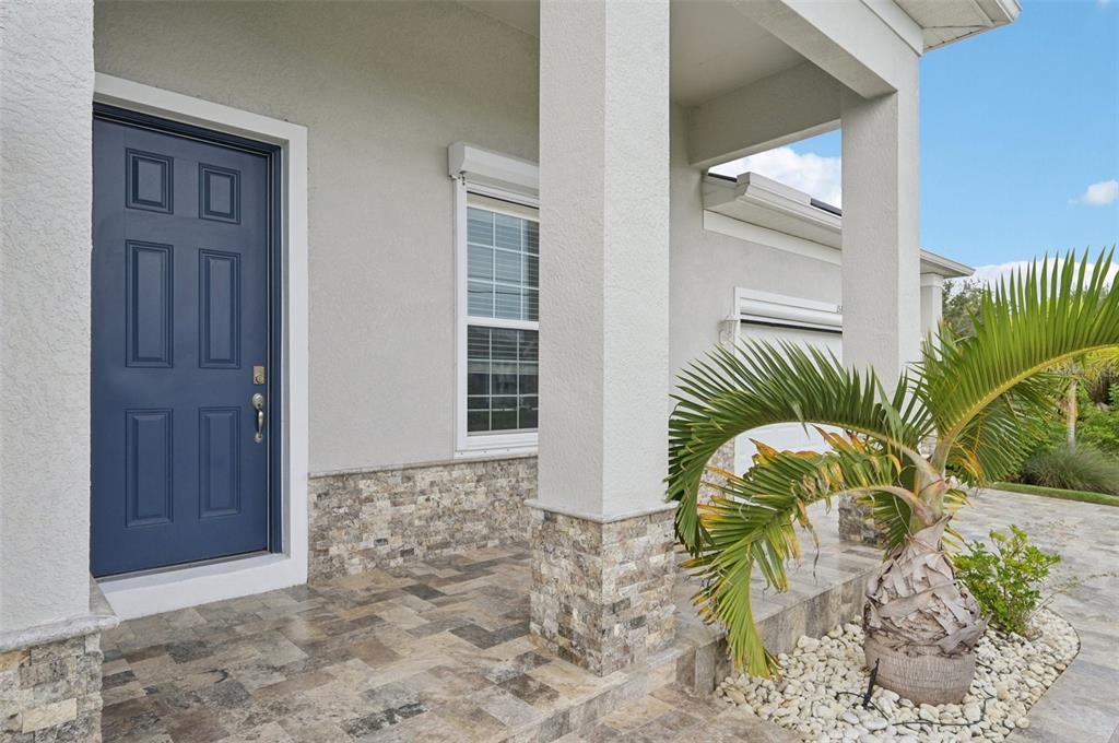 A blue front door opens onto a stone-tiled porch with a palm tree — 15301 CHINOOK WAY, PORT CHARLOTTE, FL