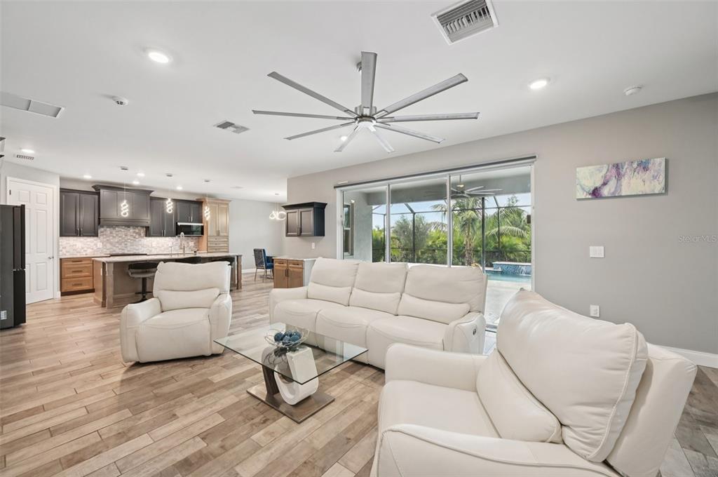 A living room with white leather furniture, a glass coffee table, and an open kitchen — 15301 CHINOOK WAY, PORT CHARLOTTE, FL