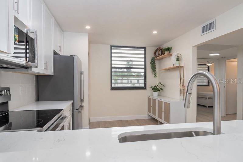 A kitchen with white cabinets, stainless steel appliances, and a quartz-topped island with a sink — 223 LAKEWOOD DRIVE UNIT 223, BRADENTON, FL