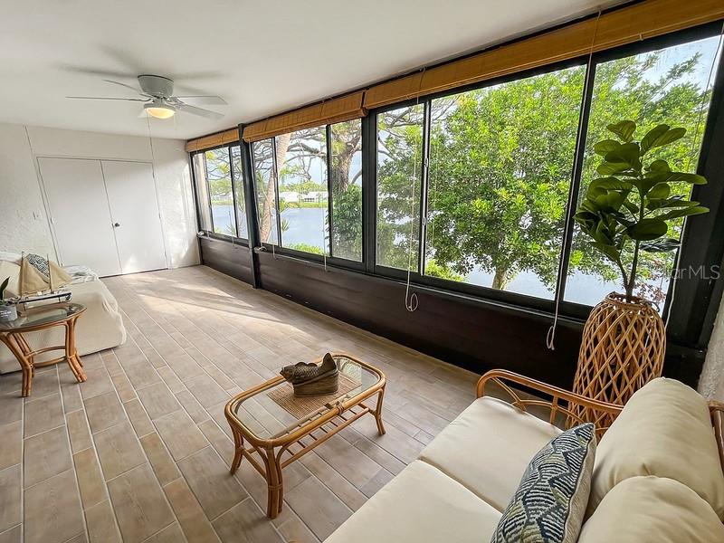 A sunroom features tile flooring, a ceiling fan, wicker furniture, and large windows overlooking water — 223 LAKEWOOD DRIVE UNIT 223, BRADENTON, FL